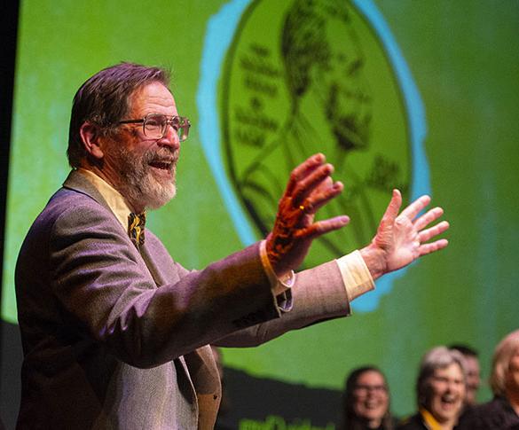 George Smith on stage with Nobel Medal illustration in background